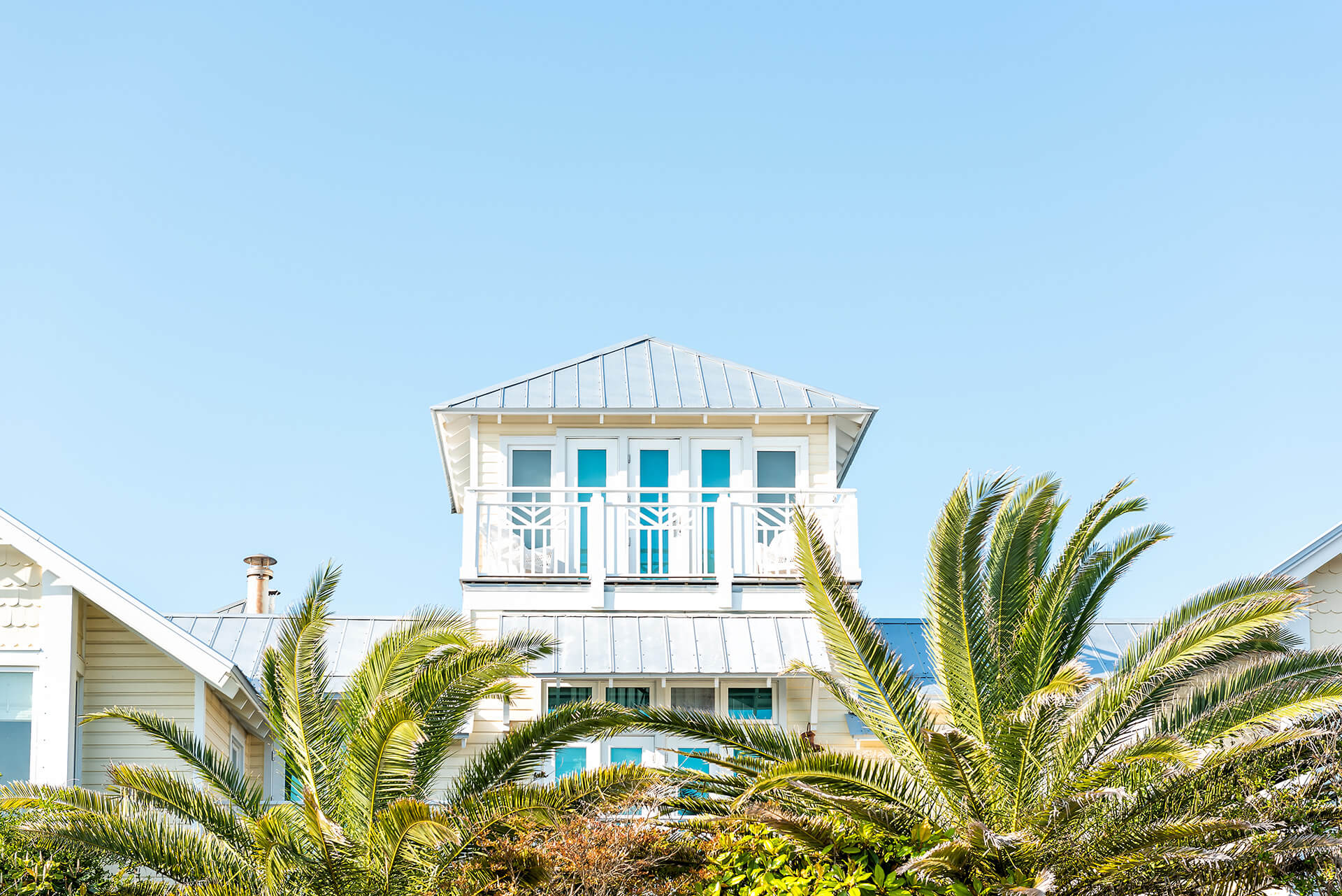 A bright Space Coast home with palm trees under a blue sky